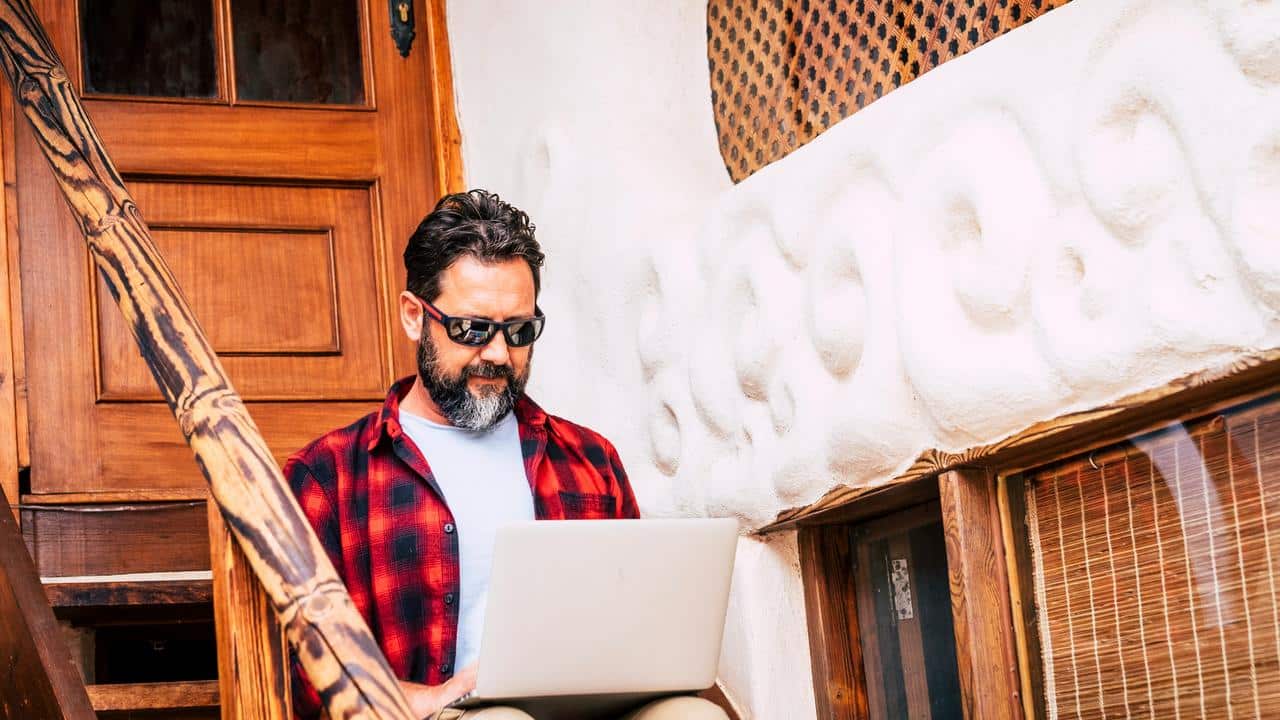 A man using a laptop outdoors.