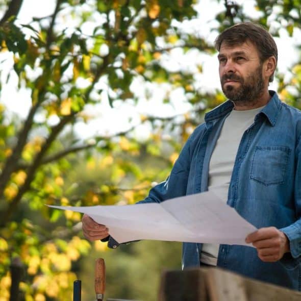 A man holding blueprints outdoors.