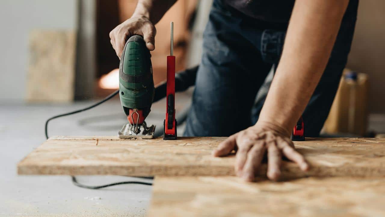 A person cutting wood with a jigsaw.