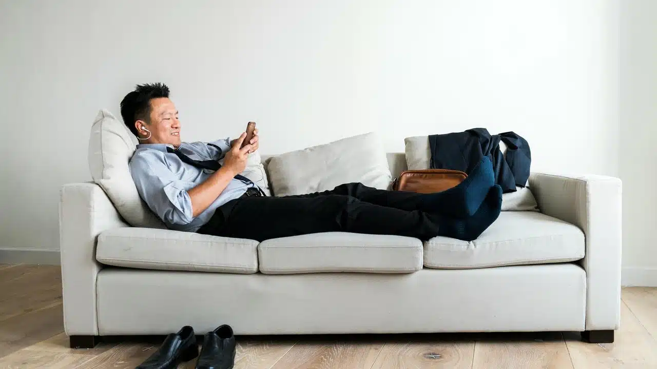 A man relaxing on a couch using a phone.