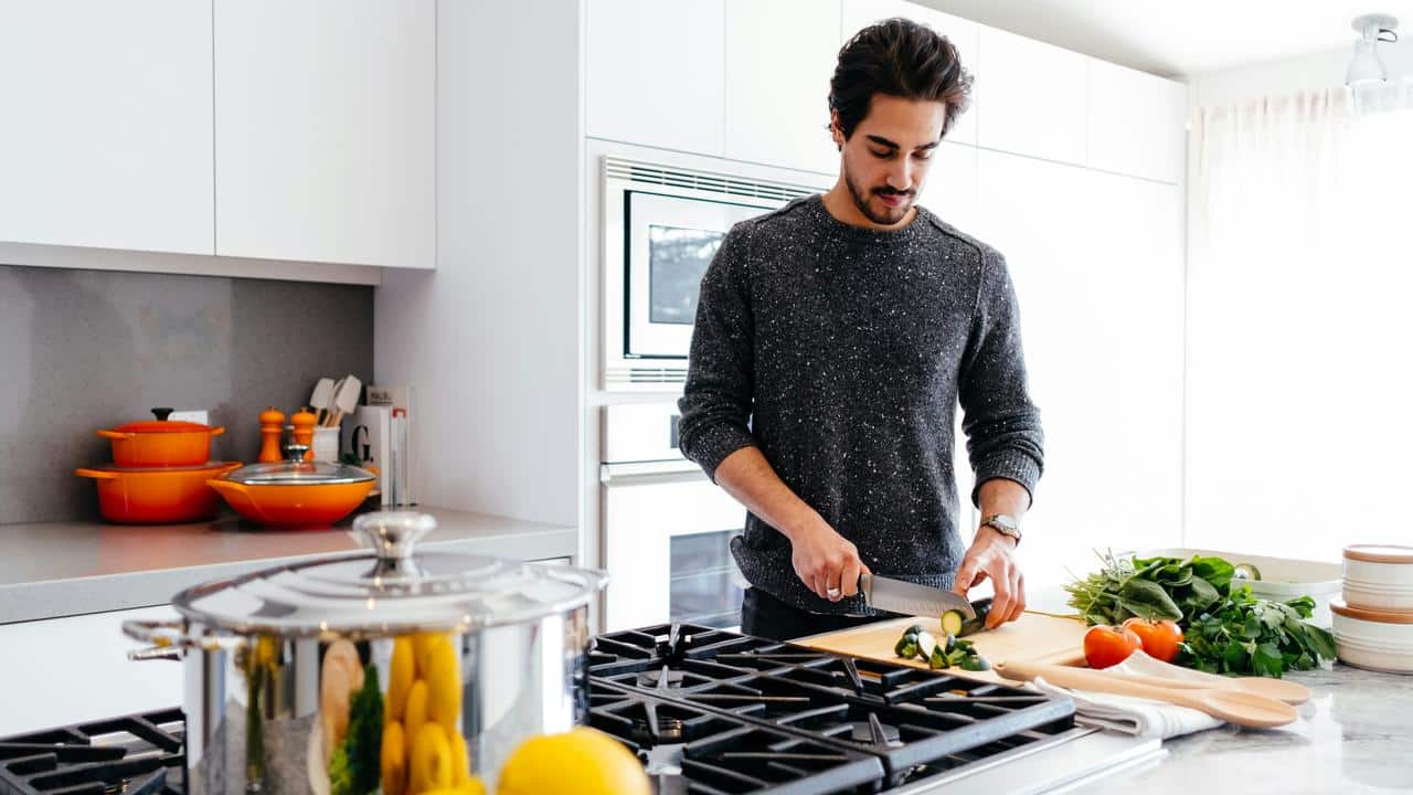 A man chopping vegetables in a kitchen.