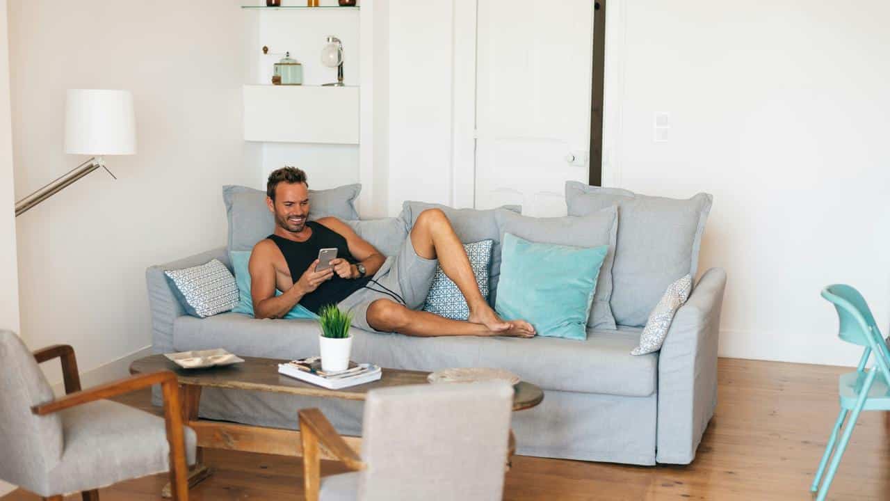 A man lounging on a couch using a phone.