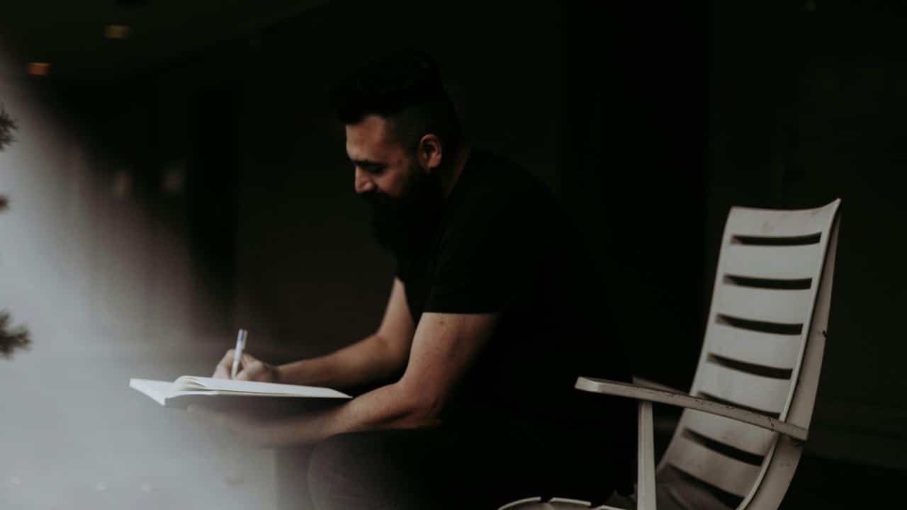 A man writing in a notebook.