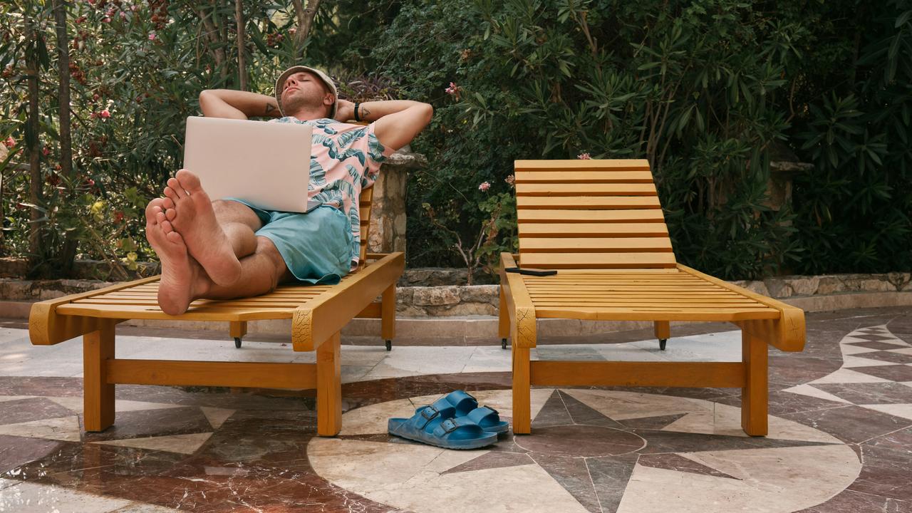 A man relaxing on a lounge chair with a laptop.