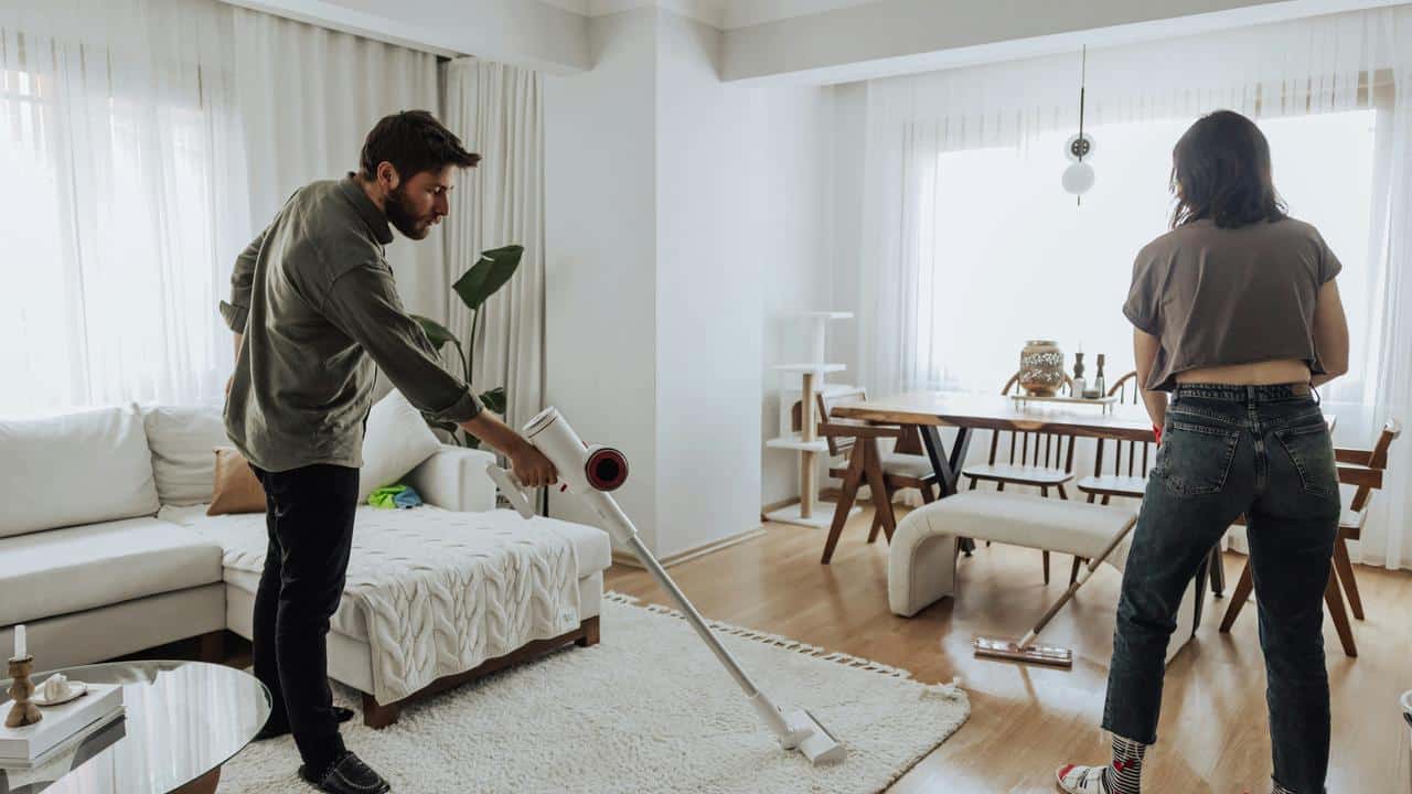 A couple cleaning a living room.