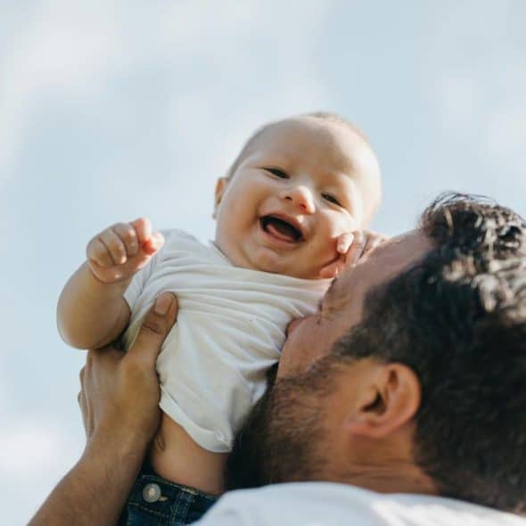 A man holding a smiling baby in the air.