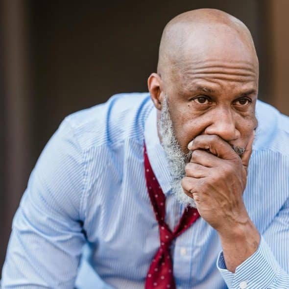 A bald man in a blue shirt looking thoughtful.