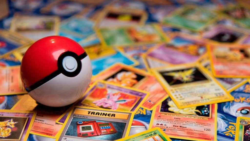 A Poké Ball resting on a pile of Pokémon trading cards.