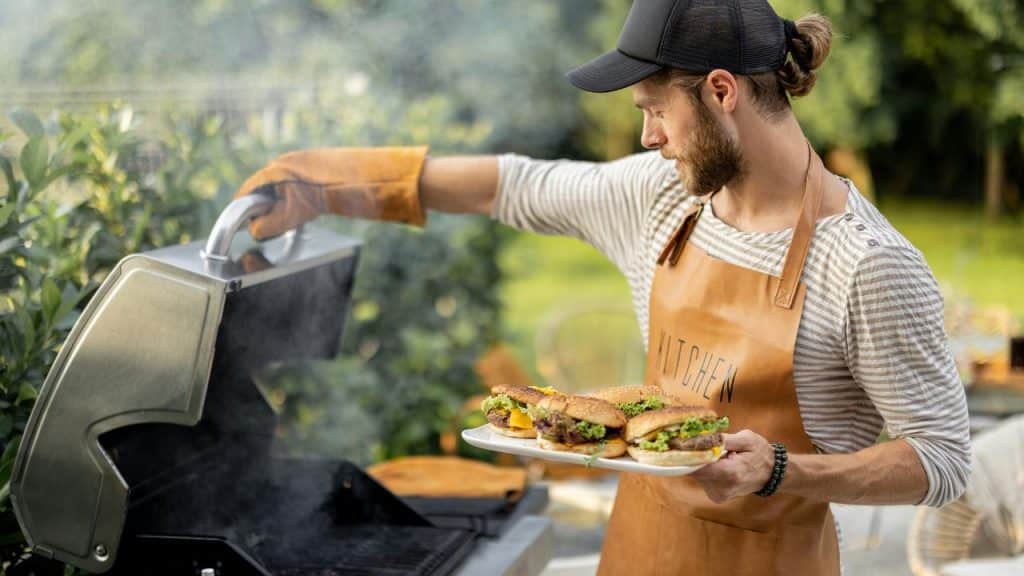 A man grilling burgers outdoors.
