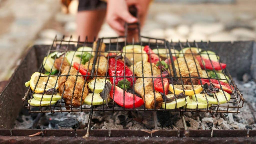 A grill basket with fish and vegetables.