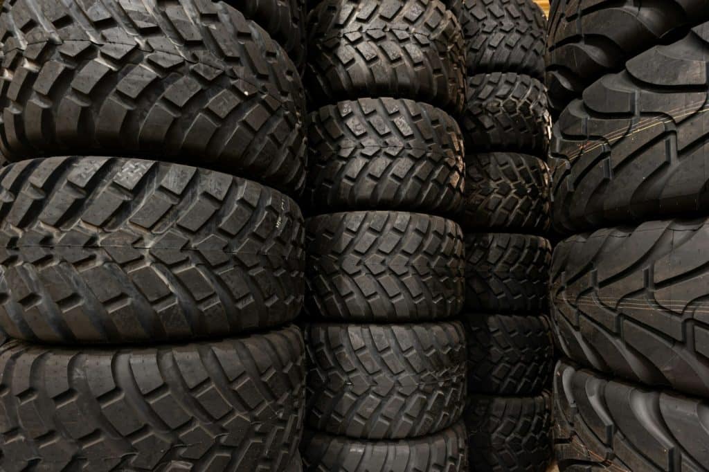Stacks of large off-road tires arranged in rows inside a storage area.