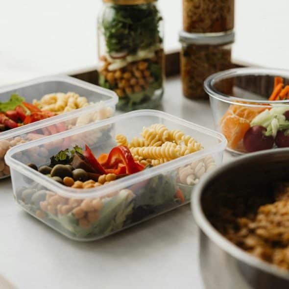 A selection of healthy meal prep containers with pasta, vegetables, and legumes.