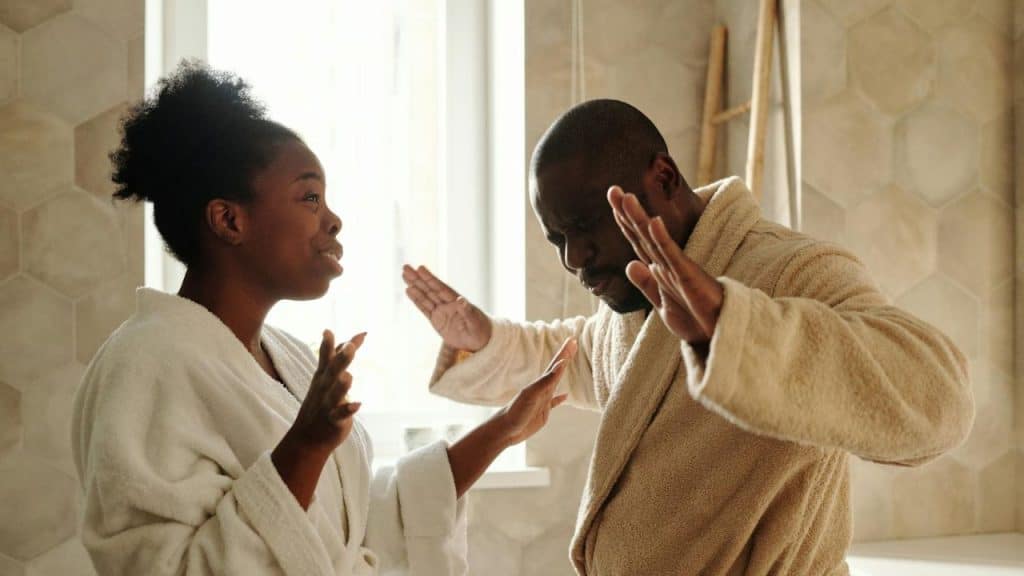 A couple in bathrobes in what appears to be a bathroom, arguing.