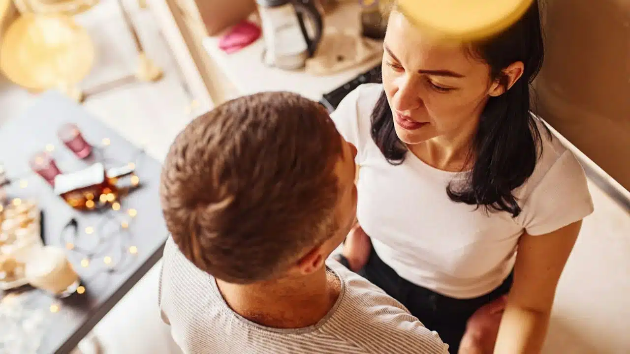 A man and woman sit close together, looking at each other, from a high angle.