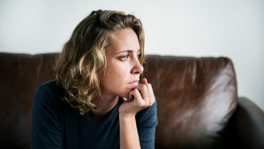 A serious woman with her hand on her chin is looking away from the camera.