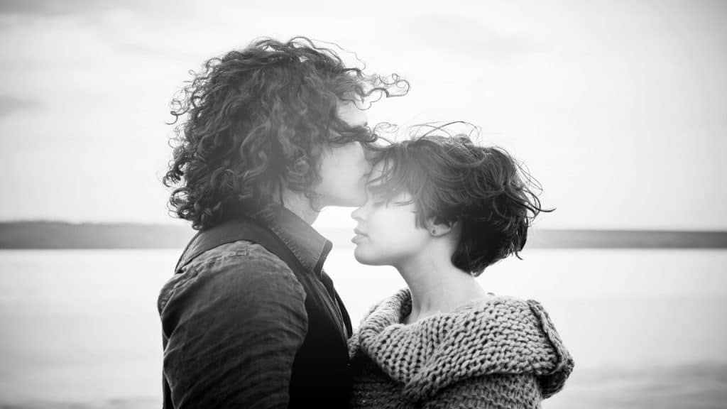 A man kissing a woman’s forehead