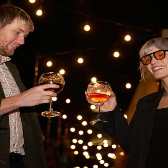 A couple toasting their wine glasses together