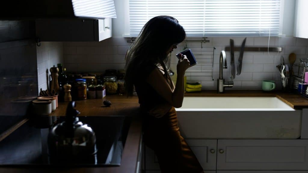 A woman looking sad in the kitchen.