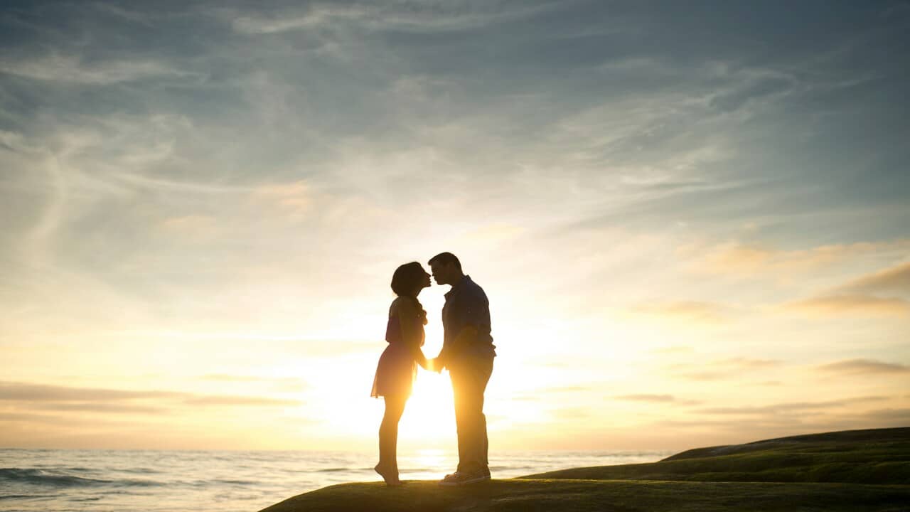 A couple about to kiss at sunset.