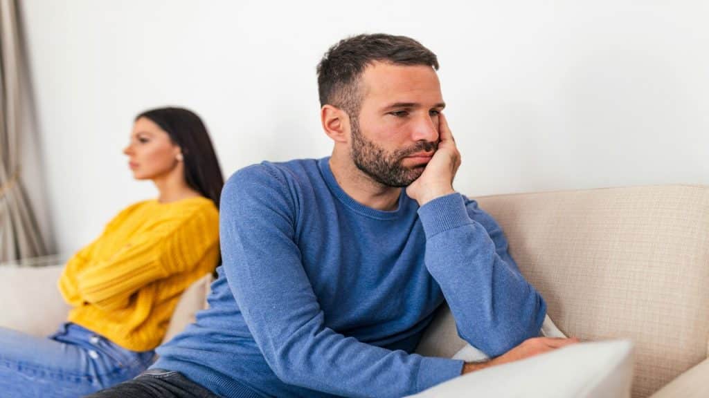 A couple looking sad on the couch.