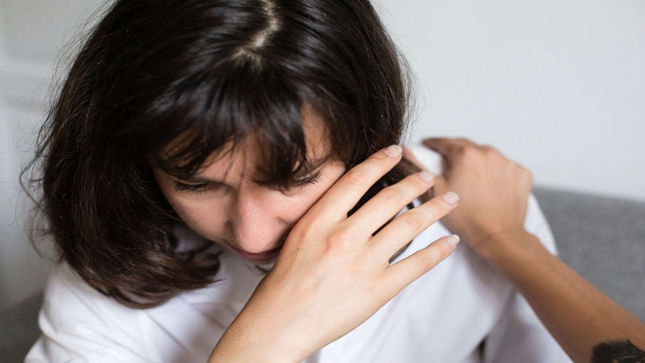 A woman being comforted by a friend at home