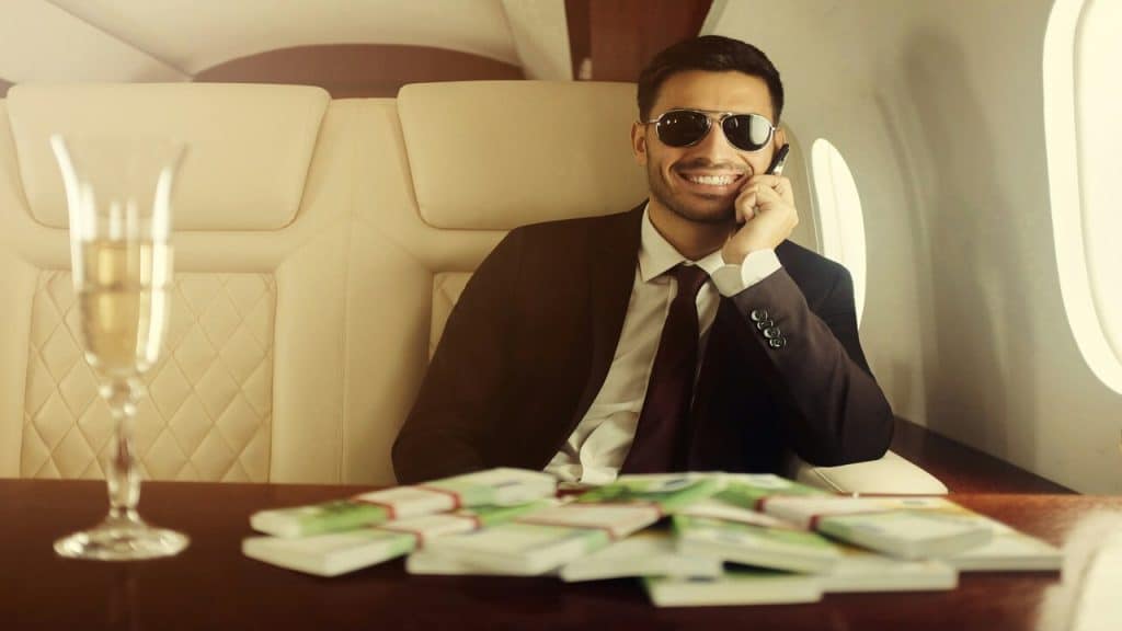A man on his private jet with wads of cash in front of him