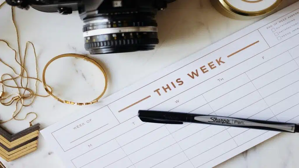 A weekly planner beside a camera