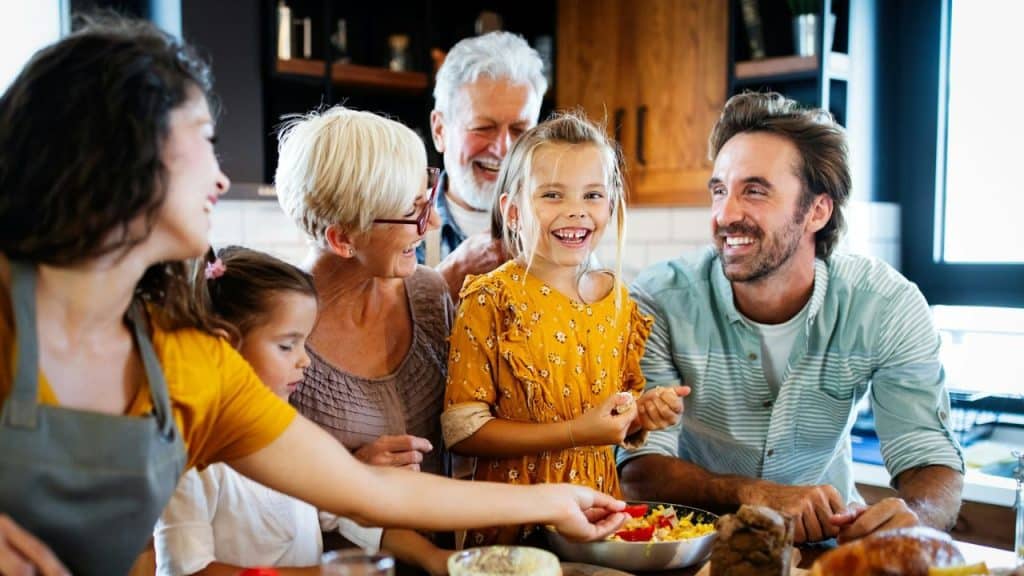 A multigenerational family smiles and laughs together at a table.