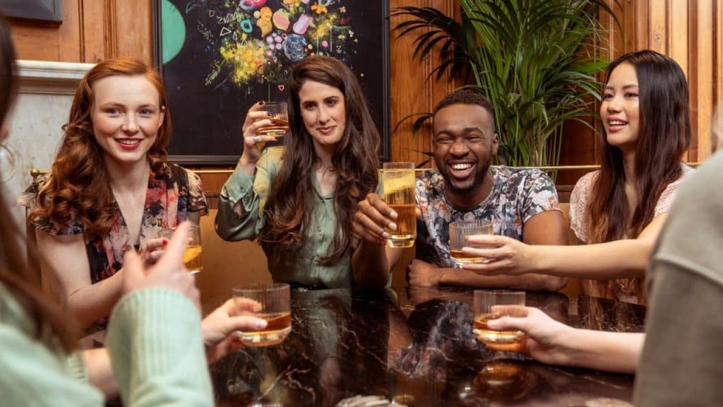 A group of diverse friends toasting with drinks at a bar.