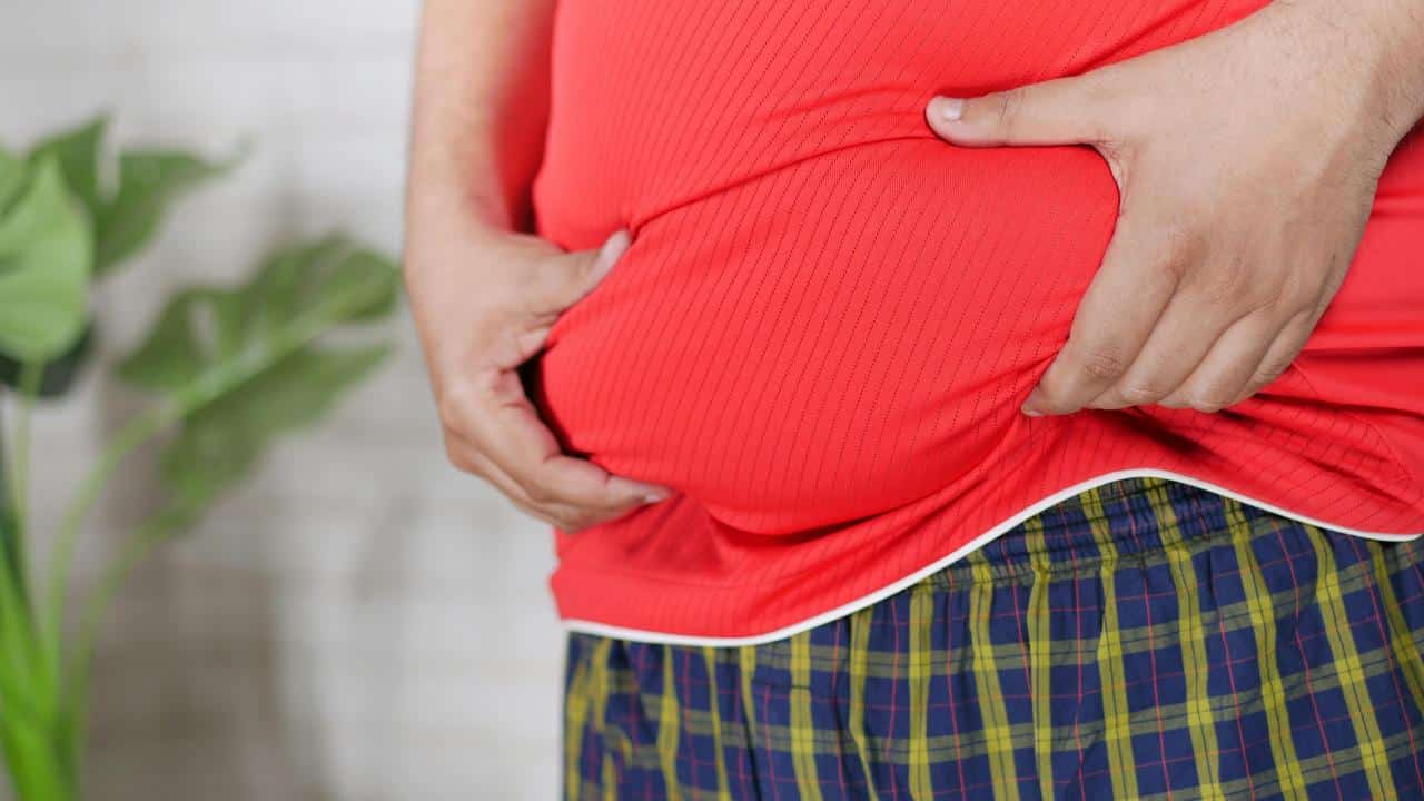 A person in a red shirt grasping their belly.