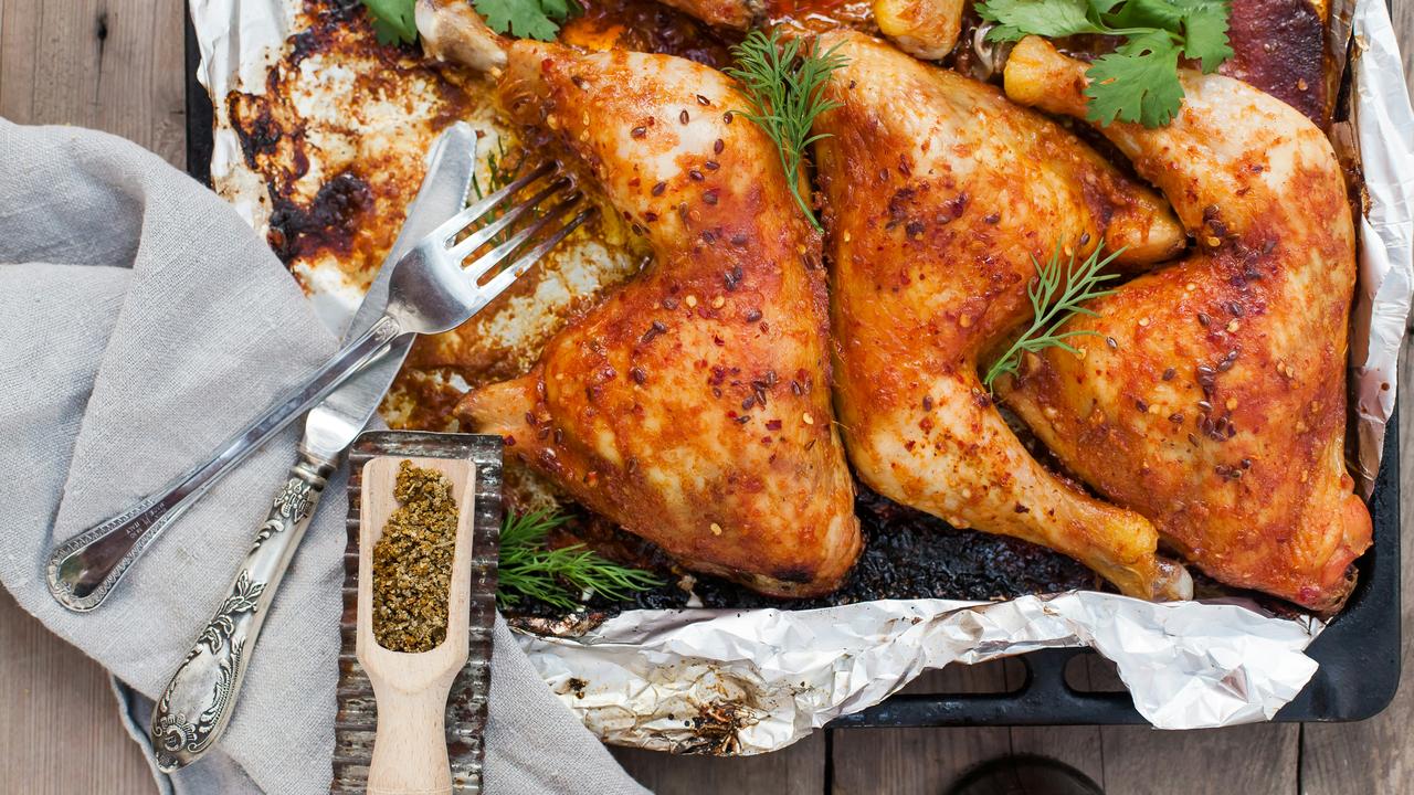 A tray of roasted chicken legs with herbs.