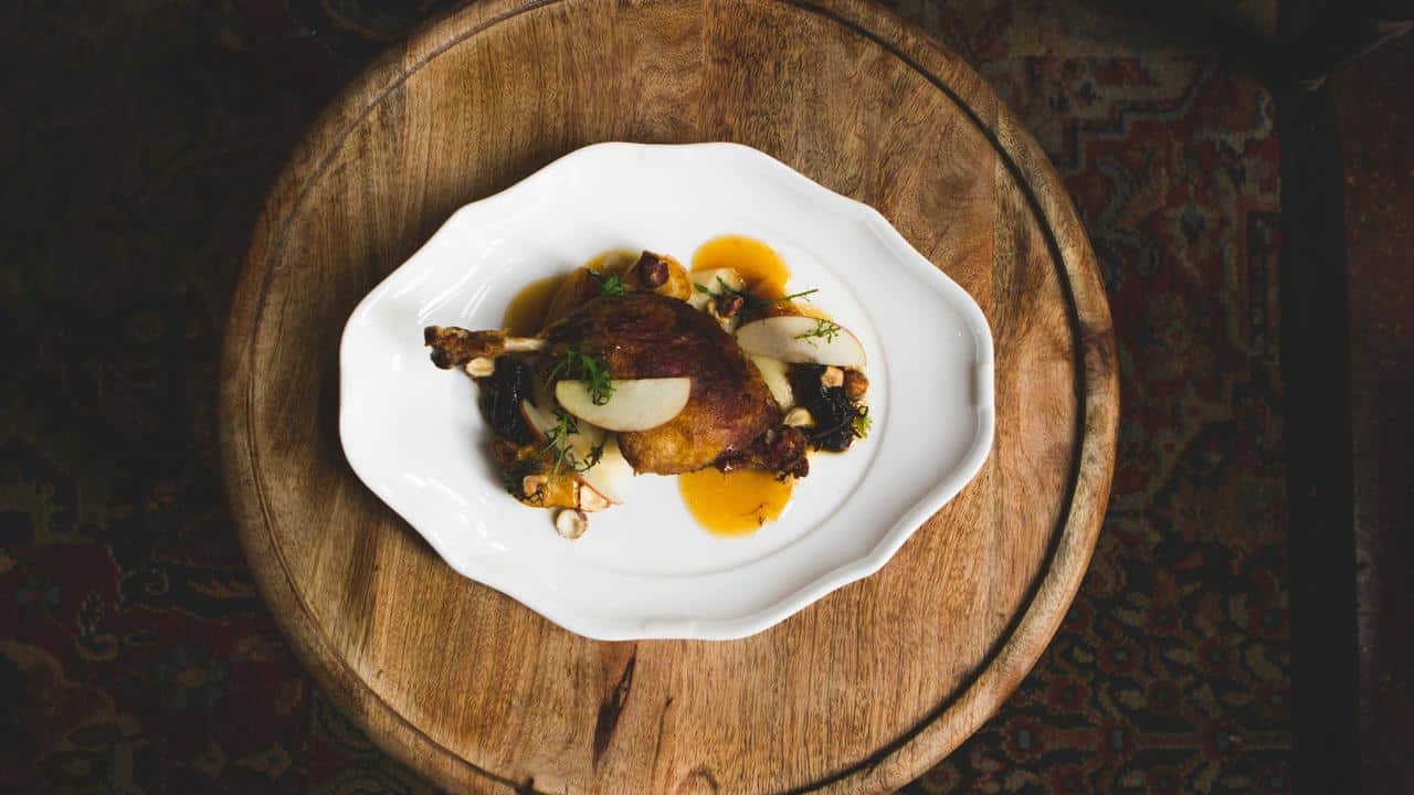A plate of roasted chicken with sauce and garnishes.