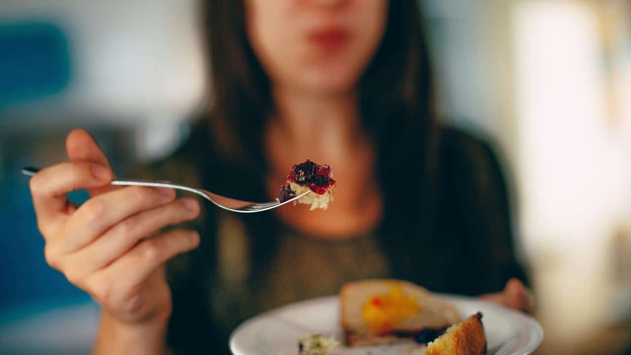 A person holding a fork with a bite of food.