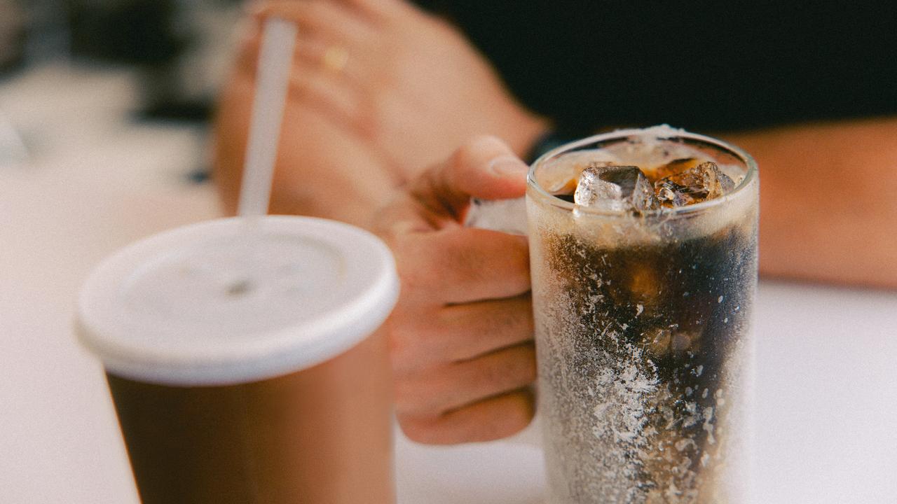 A person holding a glass of iced soda.