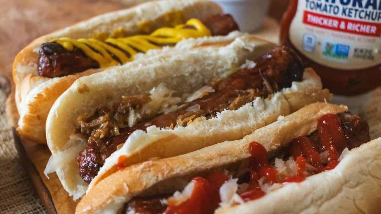 A row of hot dogs with various toppings.