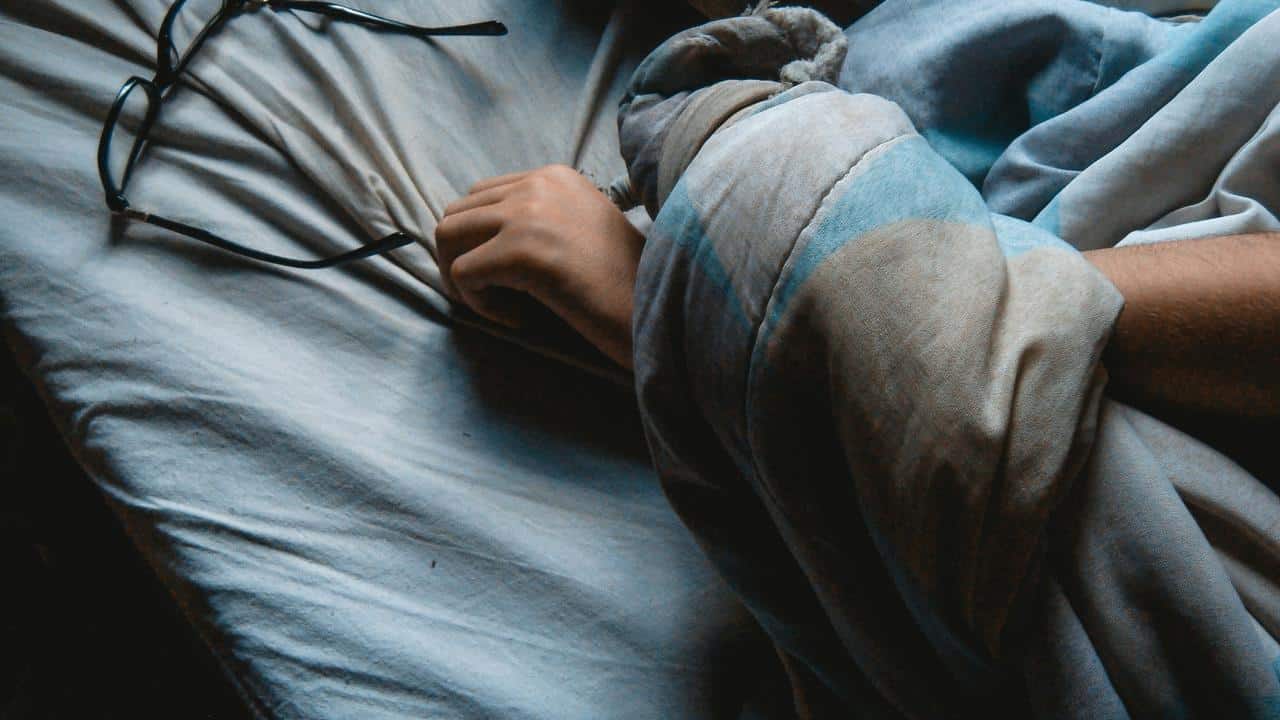 A person’s hand holding a blanket next to glasses.