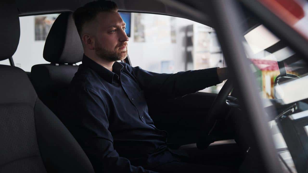 A man sitting in the driver’s seat of a car.