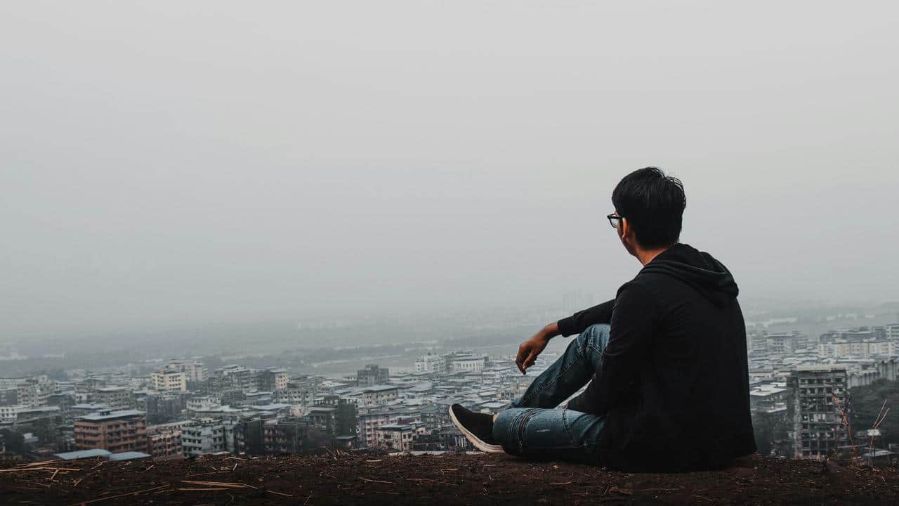 A person sitting on a hill overlooking a city.