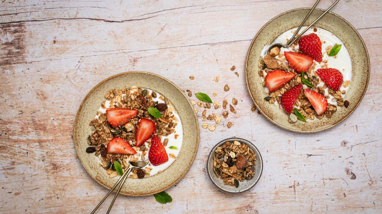 A pair of yogurt bowls with granola and strawberries.