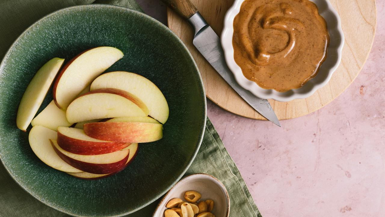 A bowl of apple slices with peanut butter.