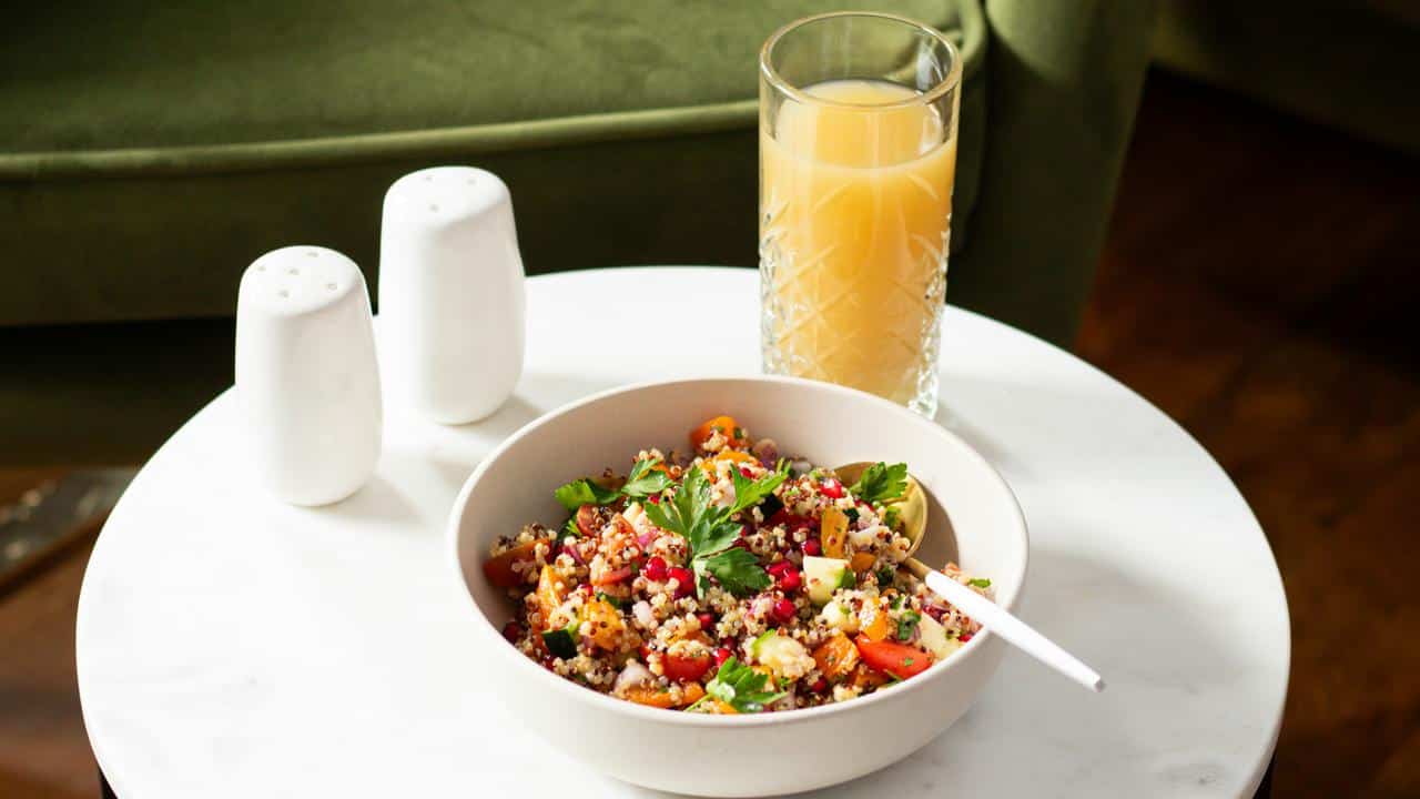 A bowl of quinoa salad with juice.