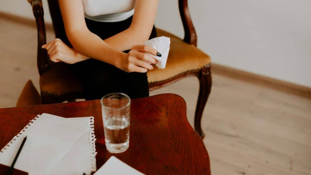A person holding a tissue at a table.