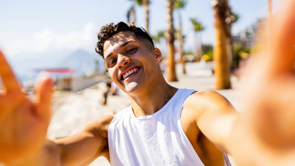 A smiling man taking a selfie outdoors.