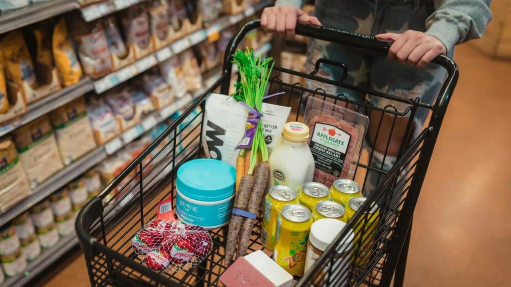A grocery cart filled with various groceries.