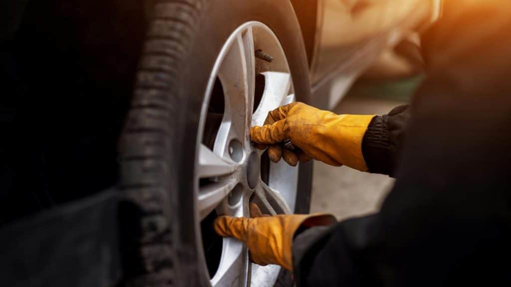A mechanic working on a car wheel.
