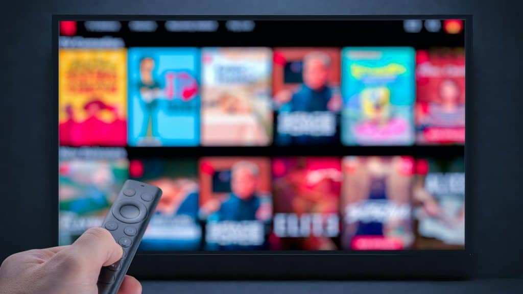 A person holding a remote in front of a TV screen.