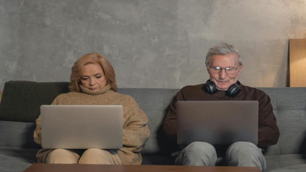 A couple sitting on the sofa using their laptops