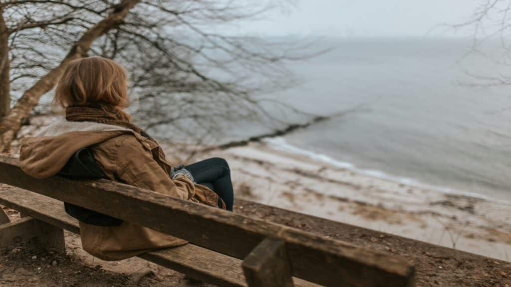 A woman sitting alone by a body of water
