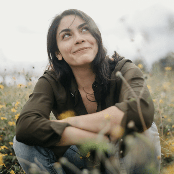 A happy woman sitting on a field of flowers