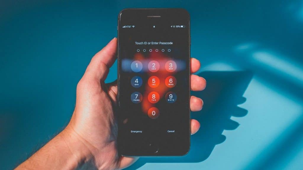 A person's hand holds a smartphone displaying a passcode screen.